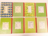 several books are lined up on a table with a white background
