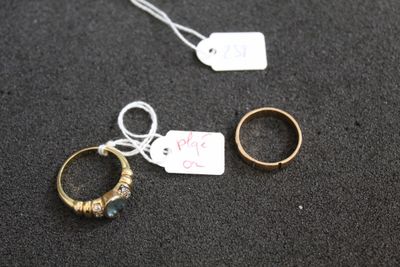 deux bagues en or et une bague en argent, avec une étiquette de prix, posées sur un fond noir