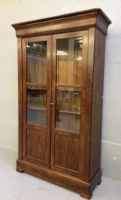 un meuble en bois avec des portes en verre dans le coin d'une pièce