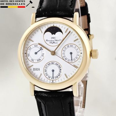 a gold wrist watch with a white dial and black leather strap