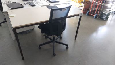 un bureau blanc avec une chaise noire et un ordinateur portable posé dessus