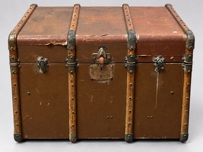 a brown trunk with metal handles on a white surface
