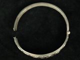 a close up of a silver bracelet on a black surface