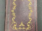 an old book with a gold design on it sitting on a table