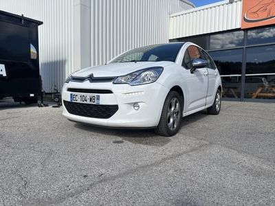 la petite voiture blanche est garée devant un bâtiment