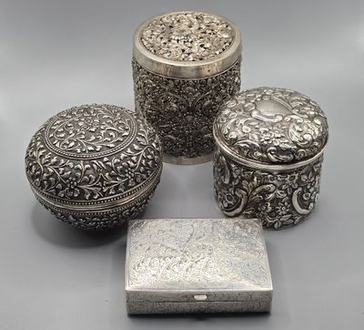 trois boîtes en argent et une boîte avec un couvercle posées sur une table