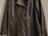 un manteau en cuir marron accroché au mur à côté d'un porte-manteau