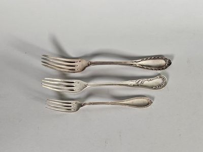 trois fourchettes et deux cuillères posées sur une surface blanche