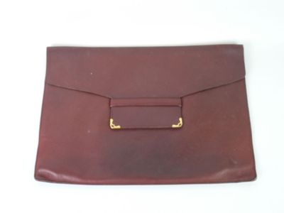 un gros plan d'un sac à main en cuir marron posé sur une surface blanche