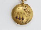 an image of a gold pocket watch with purple stones on it