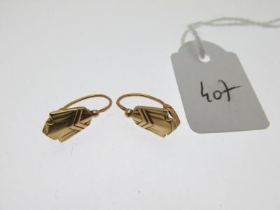 une paire de boucles d'oreilles en or avec une étiquette de prix posée sur une table blanche
