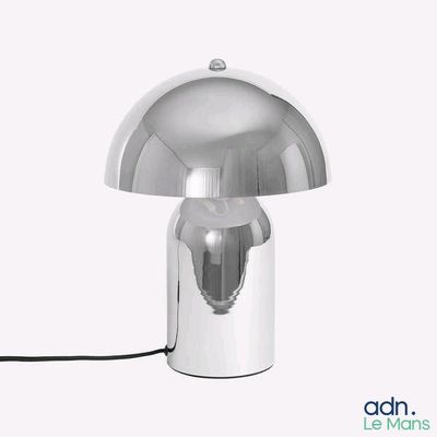 une lampe argentée posée sur une surface blanche