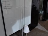 une lampe posée par terre devant un tableau blanc
