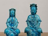 pair of blue glazed buddha figurines sitting on a table