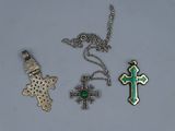 trois croix différentes et un pendentif en forme de croix sur un fond blanc
