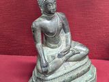 une statue de Bouddha assis sur un socle rouge