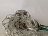 a glass flower with a green stem on a table