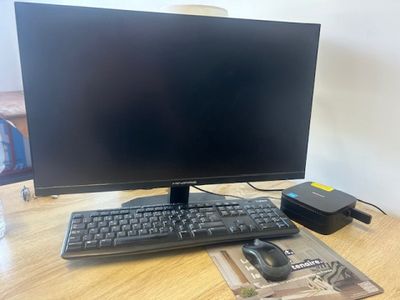 a computer monitor sitting on top of a wooden desk next to a mouse and keyboard