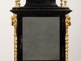 a black clock on a table with gold trimmings