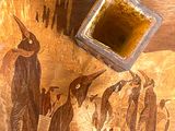 peinture représentant un groupe de manchots sur une table en bois, avec un morceau de bois carré