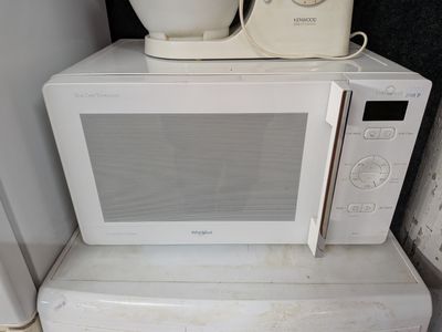 un micro-ondes blanc posé sur un four à micro-ondes