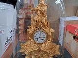une horloge en or sous un dôme de verre sur une table