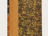 un livre à la couverture marron posé sur une table blanche