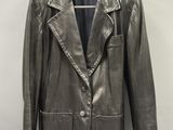une veste blazer en cuir argenté, suspendue à un cintre sur un mur blanc