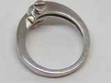 une bague en argent sertie d'un diamant, posée sur une table