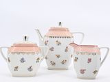 three pieces of tea set with pink and white flowers on them