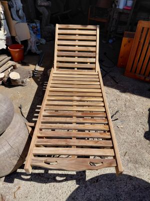 a wooden chaise lounger sitting in the middle of a yard