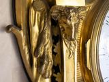 a gold clock on the wall with a statue of an angel on it
