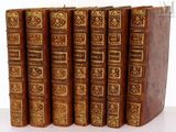 six vieux livres sont alignés sur une surface blanche