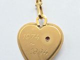 an image of a gold heart necklace with a ruby stone in the center