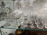 une étagère en verre sur laquelle sont posés de nombreux verres de toutes sortes