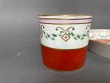 a red and white cup sitting next to a white and red bowl