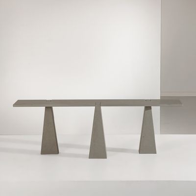 une table en béton à trois pieds posée sur une surface blanche