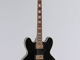 a black electric guitar sitting on top of a white surface