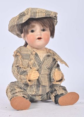 a small doll sitting on the ground wearing a hat and coat