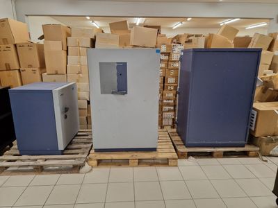 three refrigerators sitting on pallets in a warehouse