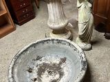 a statue of a woman holding a birdbath next to a birdbath
