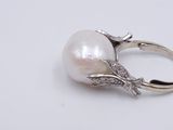 an image of a white pearl and diamond ring on a white surface