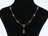 a black mannequin with a gold chain and a long pendant