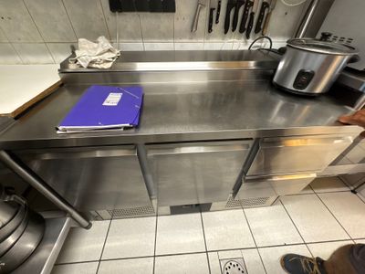une cuisine avec un plan de travail en inox et un cahier bleu posé dessus