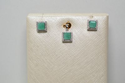 une paire de boucles d'oreilles ornées de pierres vertes et de diamants sur fond blanc
