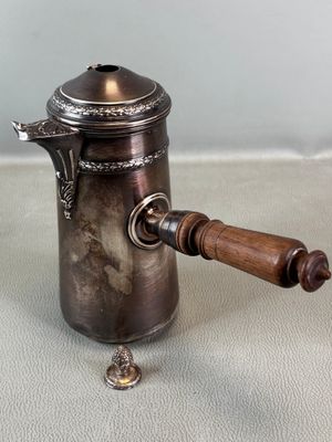 an old silver coffee pot with a wooden handle on a table