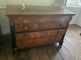 a wooden chest of drawers with a vase on top of it