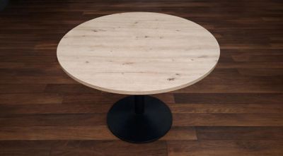 une petite table ronde avec un piètement noir posée sur un parquet