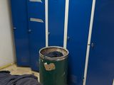 blue lockers in a room with a trash can and a trash can next to it