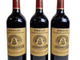 three bottles of red wine sitting next to each other on a white surface